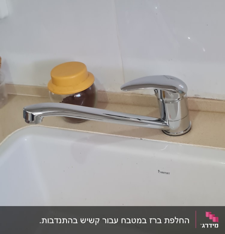 ברז מטבח כסוף מעל כיור לבן עם מגב כתום